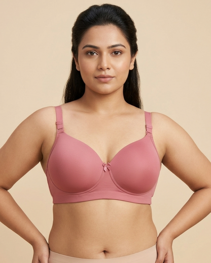 Woman wearing a pink bra and beige pants against a beige background